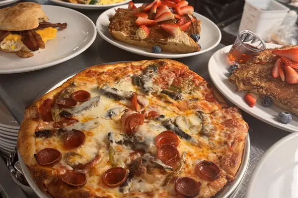 A pepperoni and mushroom pizza and brunch plates ready to go out